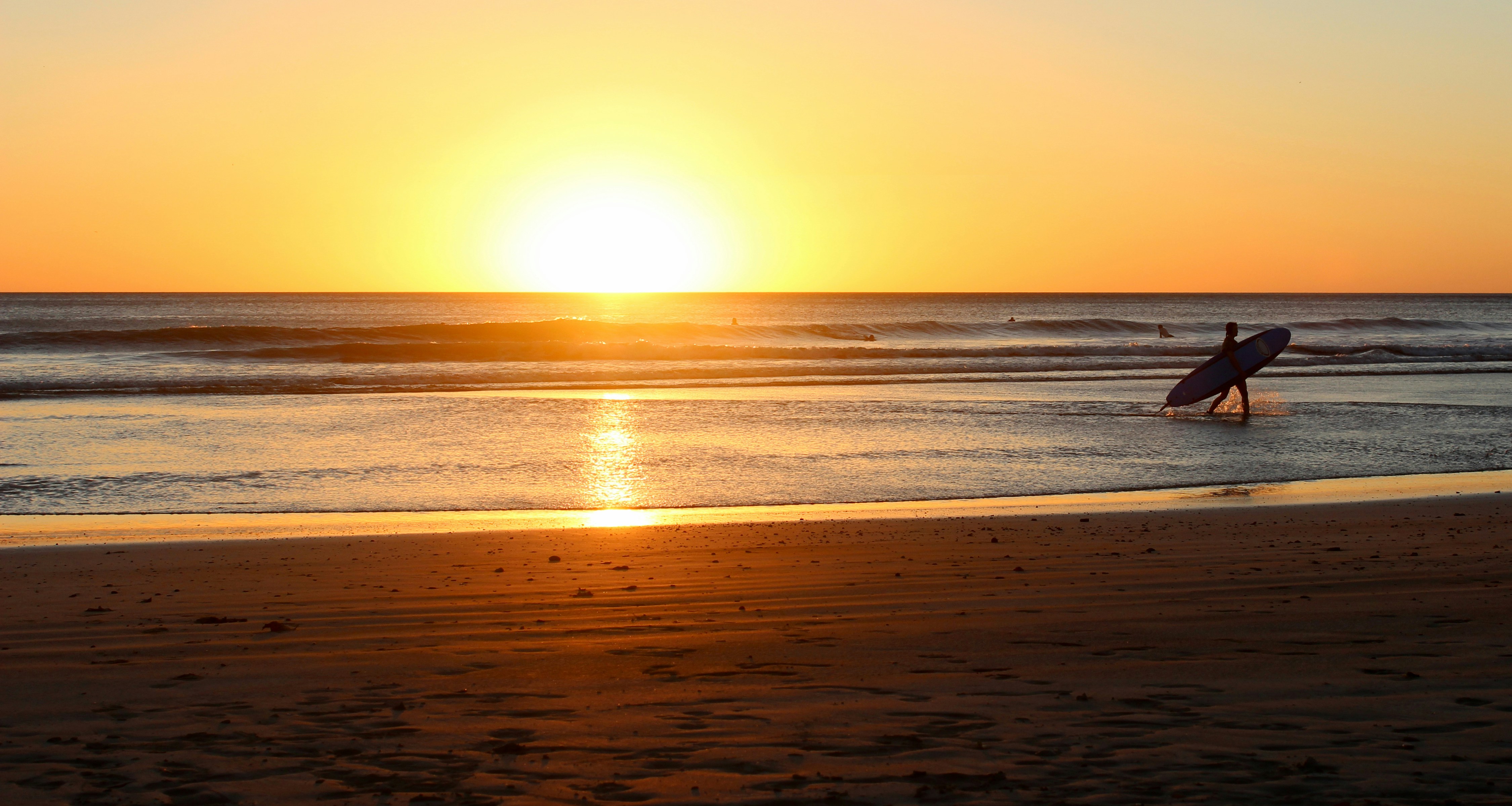 Surfer at golden hour sunset on Nicaragua's Pacific coast at Poneloya beach